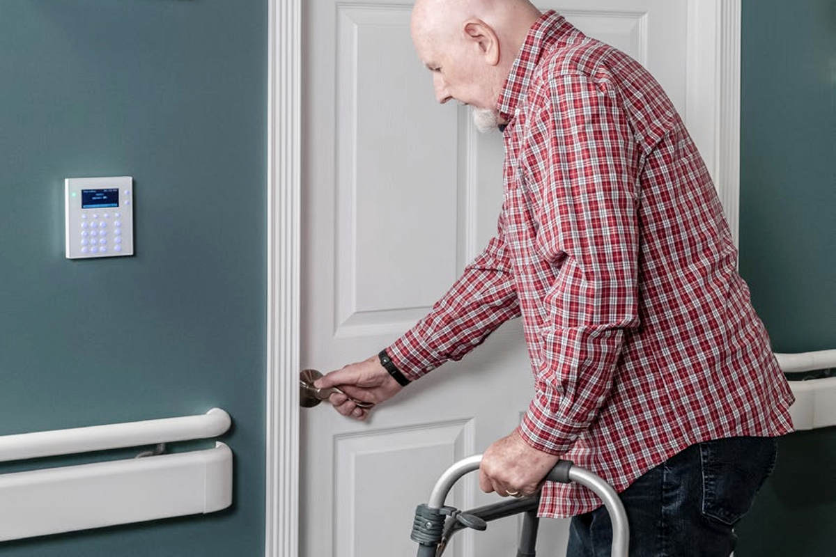 Securitas Wander Management System in action. A senior living or long term care resident opening a door equipped with Securitas access control.